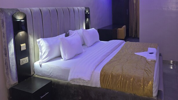 A modern bedroom with a large bed, a bedside table, and a wardrobe. - Preserve Hotel Ilupeju (Lagos)