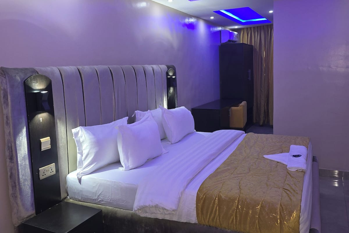 A modern bedroom with a large bed, a bedside table, and a wardrobe.