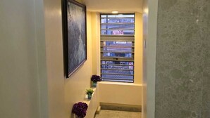 A narrow hallway with a window, a framed picture on the wall, and potted plants. - Preserve Hotel Ilupeju (Lagos)