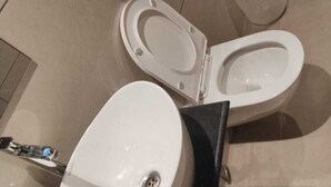 Des toilettes avec un abattant et un couvercle blancs, une base noire et un robinet chromé.
