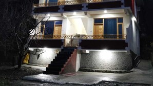 A two-story building with a balcony and a staircase leading to the entrance. - THE KAILASHA (Naggar)