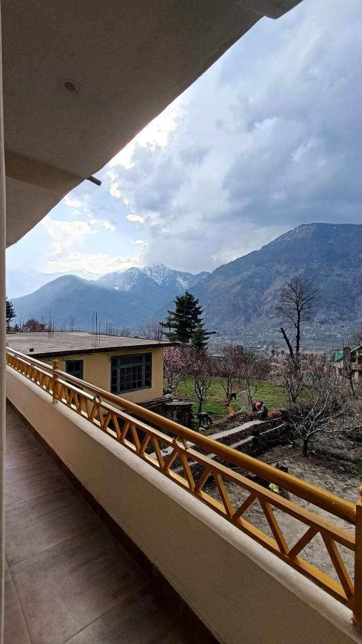 Un balcon doté d’une rambarde jaune, d’où l’on peut admirer un paysage montagneux.