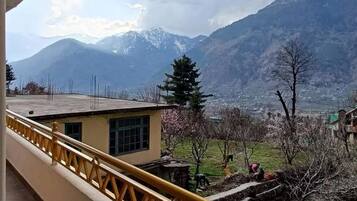 A balcony with a yellow railing overlooking a mountainous landscape.