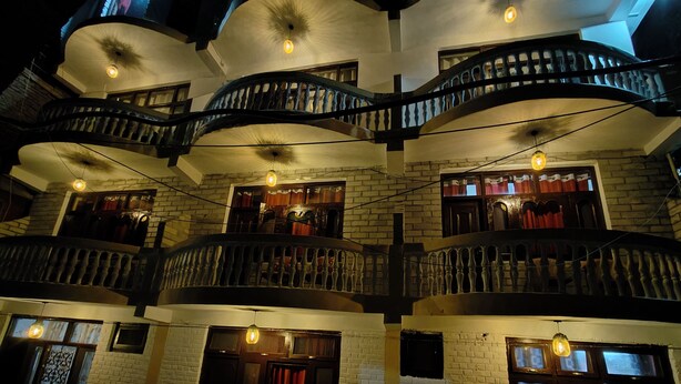 A multi-story building with a spiral staircase, multiple balconies, and hanging light fixtures. - THE KAILASHA (Naggar)