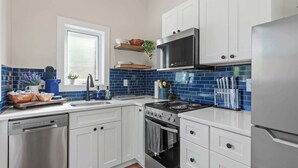 A modern kitchen with white cabinets, a stainless steel dishwasher, a built-in oven, and a microwave.