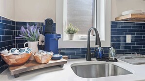 A kitchen with a modern design, featuring a built-in coffee maker, a sink, and a window with a view.