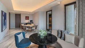 Ein modernes Wohnzimmer mit einem runden schwarzen Tisch, einem blauen Sessel und einem Sofa mit Blick ins Freie.