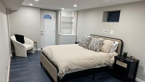 A bedroom with a bed, a chair, a nightstand, a shelf, and a door. - Spacious and Quiet 4 Bedroom House 5min Drive to DC (Arlington)