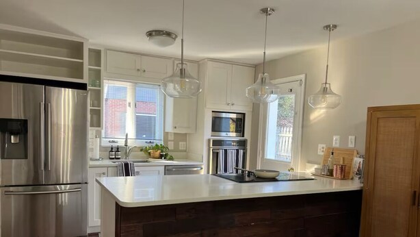 A modern kitchen with stainless steel appliances, a large island, and pendant lighting. - Spacious and Quiet 4 Bedroom House 5min Drive to DC (Arlington)