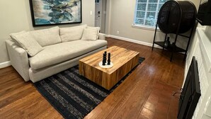A modern living room with a beige sofa, a wooden coffee table, and a black rug. - Spacious and Quiet 4 Bedroom House 5min Drive to DC (Arlington)