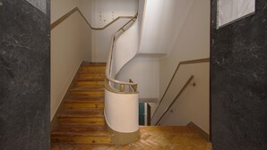 A spiral staircase with wooden steps and a white handrail, leading to an upper floor. - Alameda Typical by Homing (Lisbon)