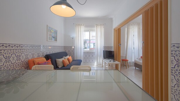 A modern living room with a sofa, TV, and glass table. - Alameda Typical by Homing (Lisbon)