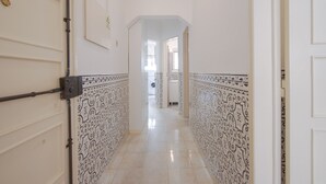 A hallway with patterned walls and a door on the left. - Alameda Typical by Homing (Lisbon)