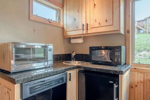 A compact kitchen with a built-in oven, microwave, dishwasher, and a window providing a view of the outdoors. - Treasury House, hot tub, sauna, pet ok, walk to the slopes! (Crested Butte)