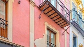 A street view with a pink building featuring a boutique named "Ana Valencia" and a store named "LACOUER." - Genteel Home Francos VIII (Seville)