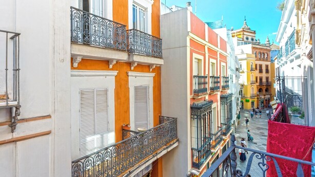 A narrow street with buildings featuring balconies and shutters. - Genteel Home Francos VIII (Seville)