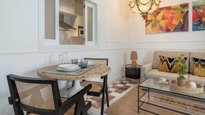 A dining area with a round table, chairs, and a chandelier. There is a sofa with cushions and a painting on the wall. - Genteel Home Francos VIII (Seville)