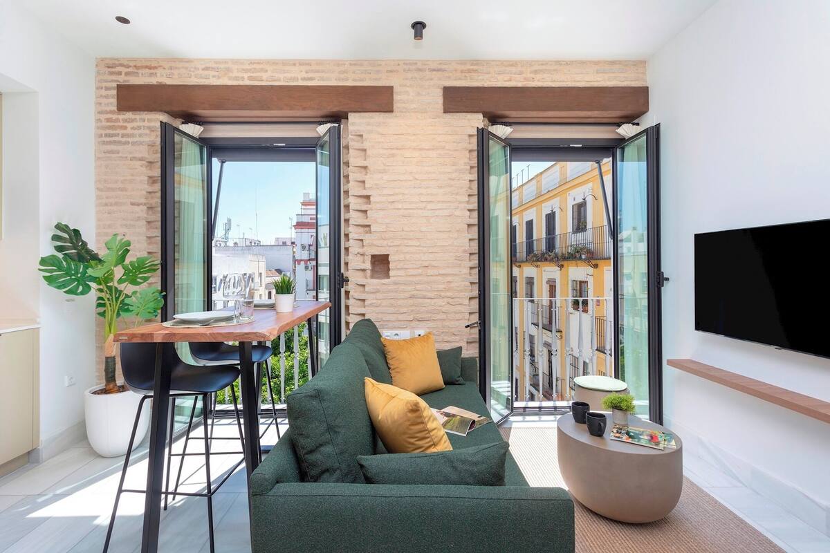 A modern living room with a green sofa, a wooden table, and a round coffee table.