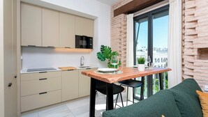 A modern kitchen with a wooden table, a green sofa, and a view of the city through large windows. - Genteel Home San Vicente (Seville)