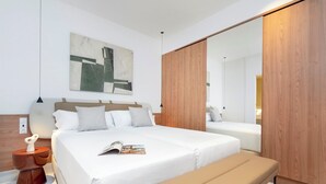 A modern bedroom with a large bed, a bench, a wooden wardrobe, and a painting on the wall. - Genteel Home San Vicente (Seville)