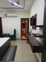Una habitación de hotel con cama, una silla, un escritorio con lavamanos y un televisor.