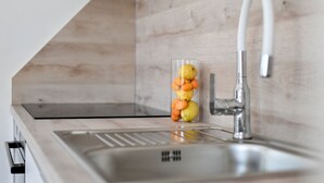 Eine moderne Küche mit Spüle aus Edelstahl, einer Holzrückwand und einer transparenten Schüssel mit Zitronen und Orangen.