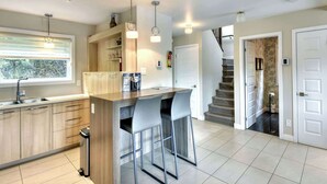 Een moderne keuken met een bar, houten keukenkastjes en een trap naar een hoger niveau.