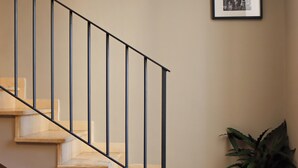 A staircase with a black metal railing, beige walls, and a potted plant on the landing. - All'Ombra Della Reggia (Caserta)