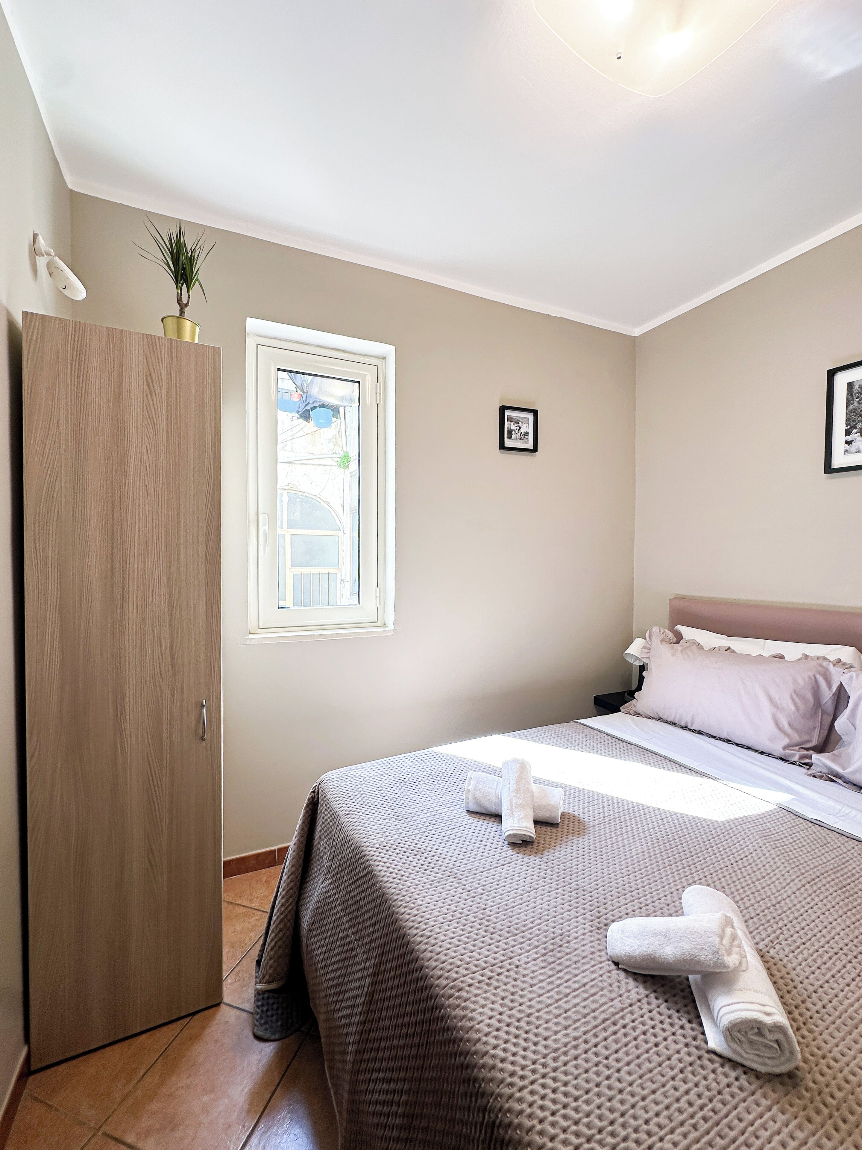Una camera da letto con un letto, un armadio, una finestra e una piccola cornice con un'immagine appesa al muro.