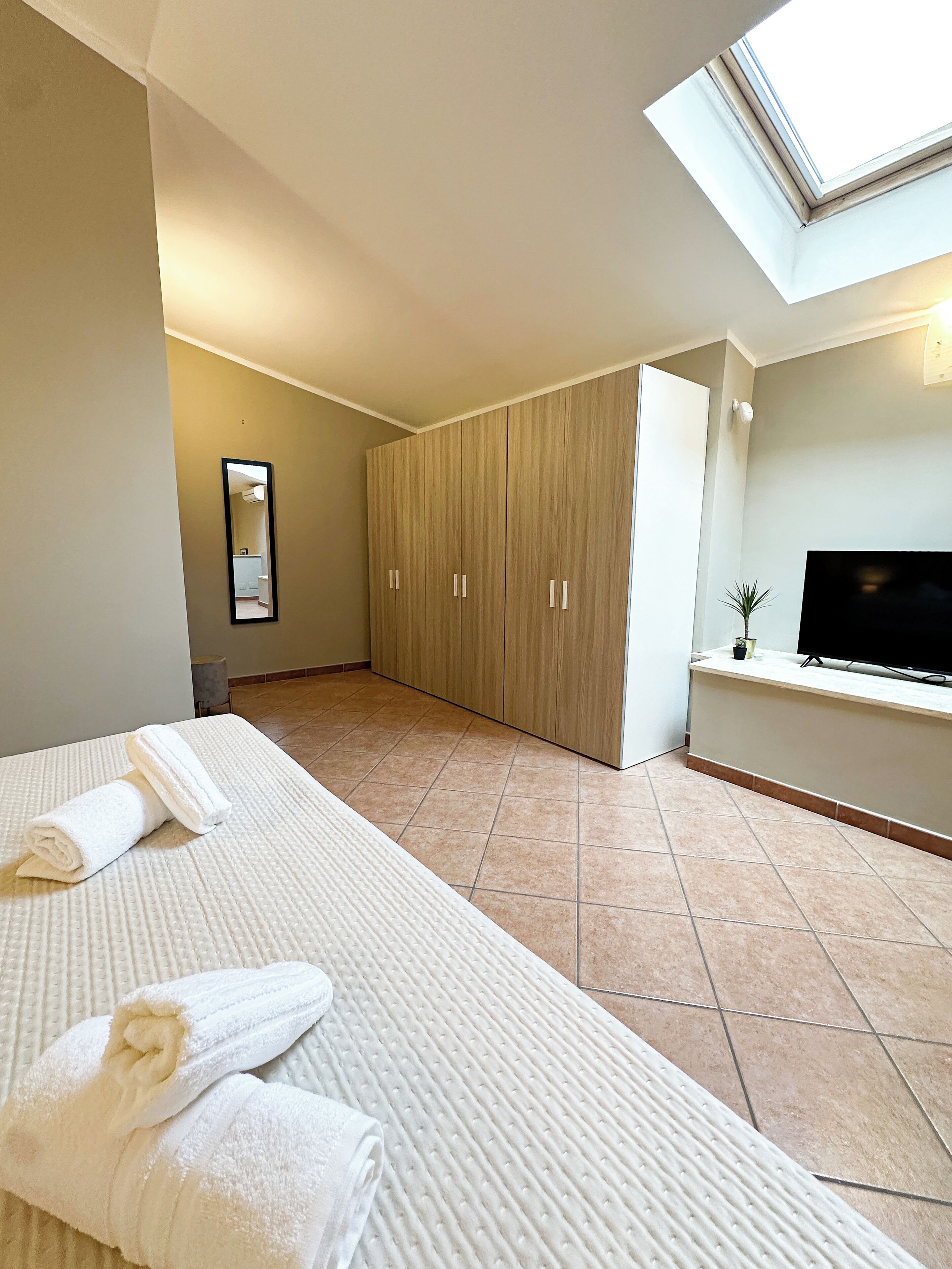 Une chambre d’hôtel avec un lit, une télévision, une armoire et une lucarne.