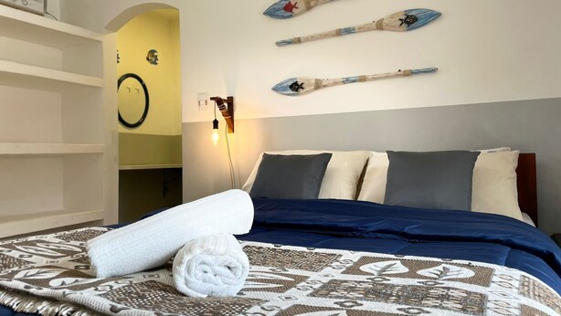 Ein Hotelzimmer mit einem Bett, einer Wandleuchte und drei Kajaks, die an der Wand präsentiert werden.