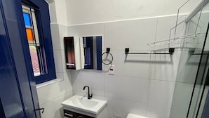 Ein kleines Badezimmer mit einem weißen Waschbecken, einer Toilette und einer Duschkabine aus Glas.