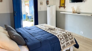 Ein Schlafzimmer mit einem Bett, einem Fernseher, einem Kleiderschrank und einer Tür, die auf einen Balkon führt.
