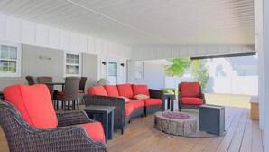 A covered patio area with wicker furniture, a stone fire pit, and a small table.