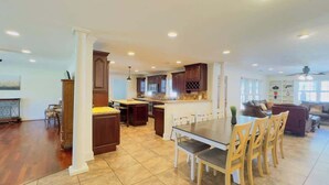 A spacious kitchen with a large island, dark wooden cabinets, and a dining area with a long table and chairs.