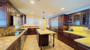 A modern kitchen with dark wood cabinets, a central island, and built-in appliances.
