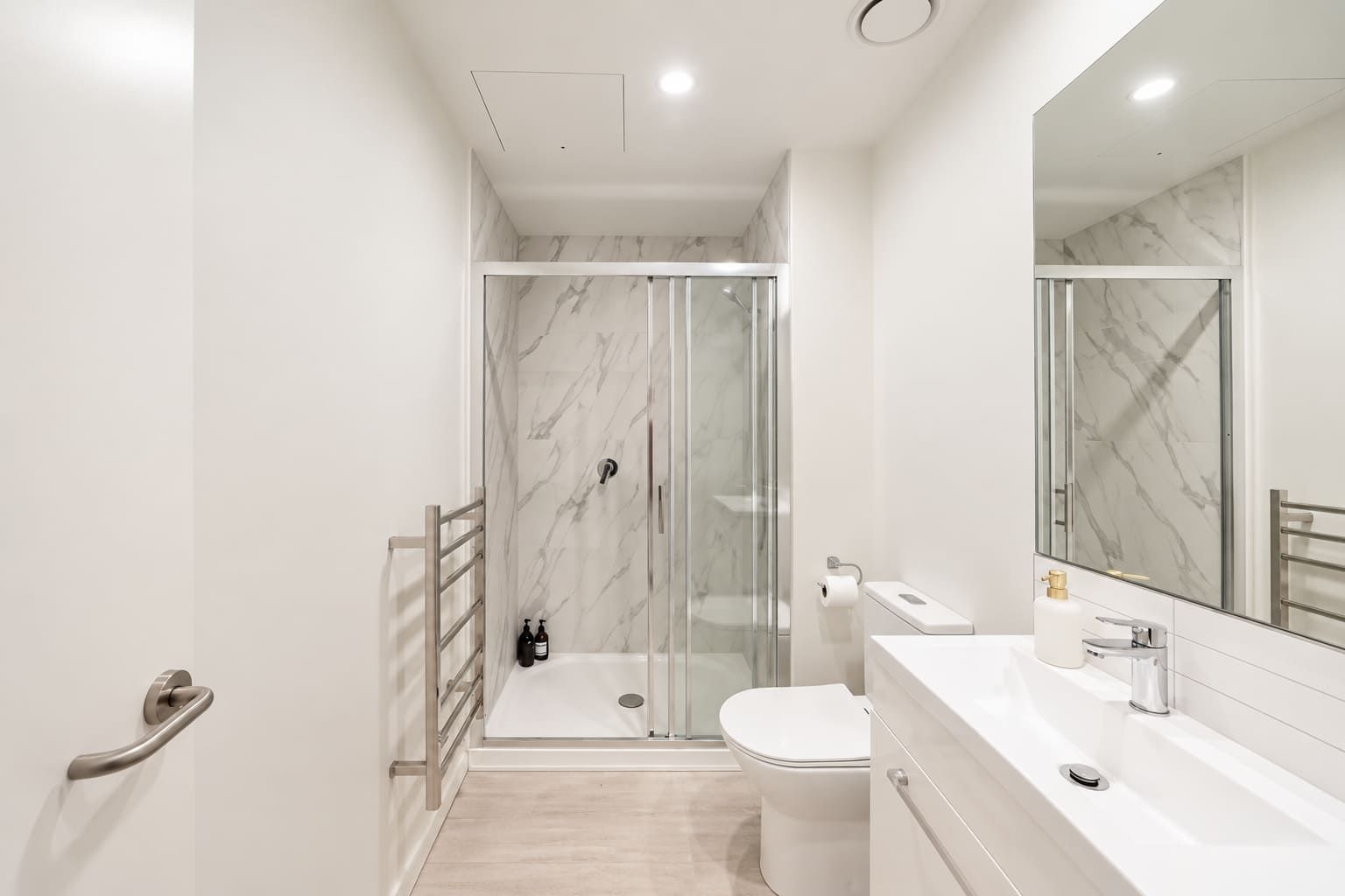 Un baño moderno con ducha envuelta en vidrio, inodoro y tocador con espejo.