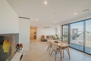 Una sala de estar moderna con televisor de pantalla plana, una mesa de comedor de madera y un ventanal con vistas a la ciudad.