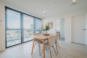 A modern dining area with a round table, six chairs, and a vase of flowers.