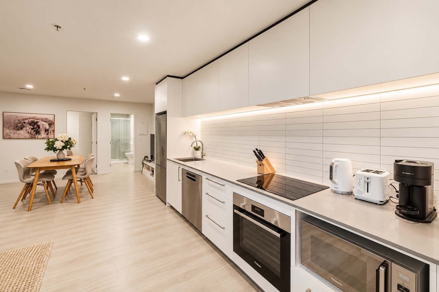 Una cocina moderna con comedor, que cuenta con electrodomésticos de acero inoxidable, cafetera y tostadora.