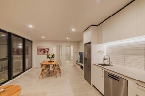 A modern kitchen with a dishwasher, a dining area with a table and chairs, and a large window with a view.