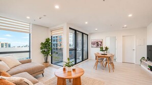A modern living room with a sofa, a round coffee table, and a dining area with a table and chairs.