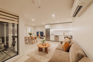 A modern living room with a sofa, coffee table, and dining area.