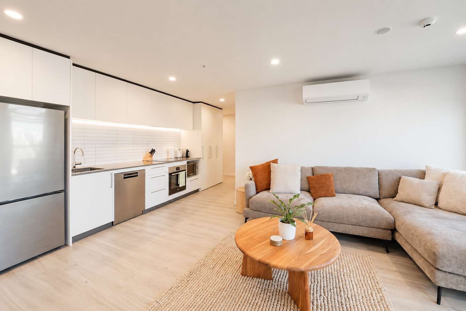 Una cocina moderna con armarios blancos, un refrigerador de acero inoxidable y un horno empotrado.