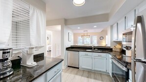 A modern kitchen with white cabinets, a black countertop, and stainless steel appliances. - 2 Bedroom in the center of the resort (Hilton Head)