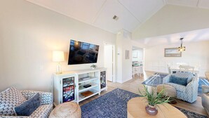 A modern living room with a flat-screen TV, a white entertainment unit, patterned sofas, and a dining area with a white table and chairs. - 2 Bedroom in the center of the resort (Hilton Head)