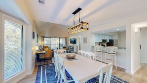 A spacious living room with a large dining table, white chairs, and a blue patterned rug. - 2 Bedroom in the center of the resort (Hilton Head)