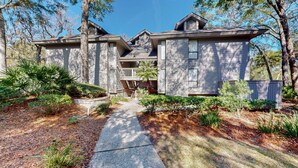 A two-story house with a covered porch, a driveway, and a well-maintained garden. - 2 Bedroom in the center of the resort (Hilton Head)