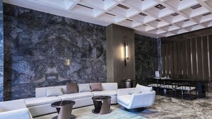 A modern lobby with a marble wall, a sofa, two side tables, and a bar area. - KEEJOY HOTEL (Fuzhou)