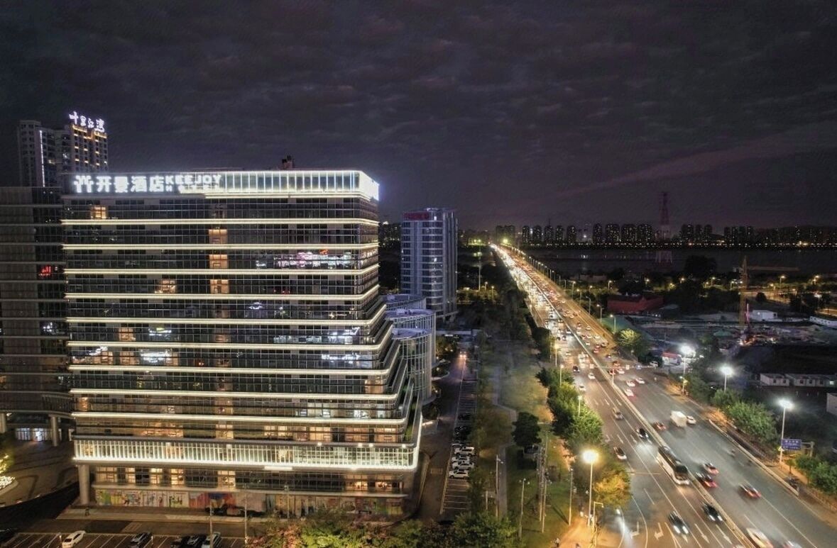 Ein mehrstöckiges Hotel mit moderner Glasfassade, direkt neben einer vielbefahrenen Autobahn gelegen.